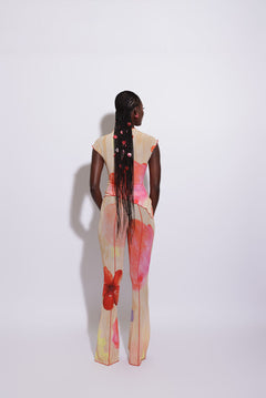 A model wearing flared mesh pants with a floral pattern, viewed from the back.